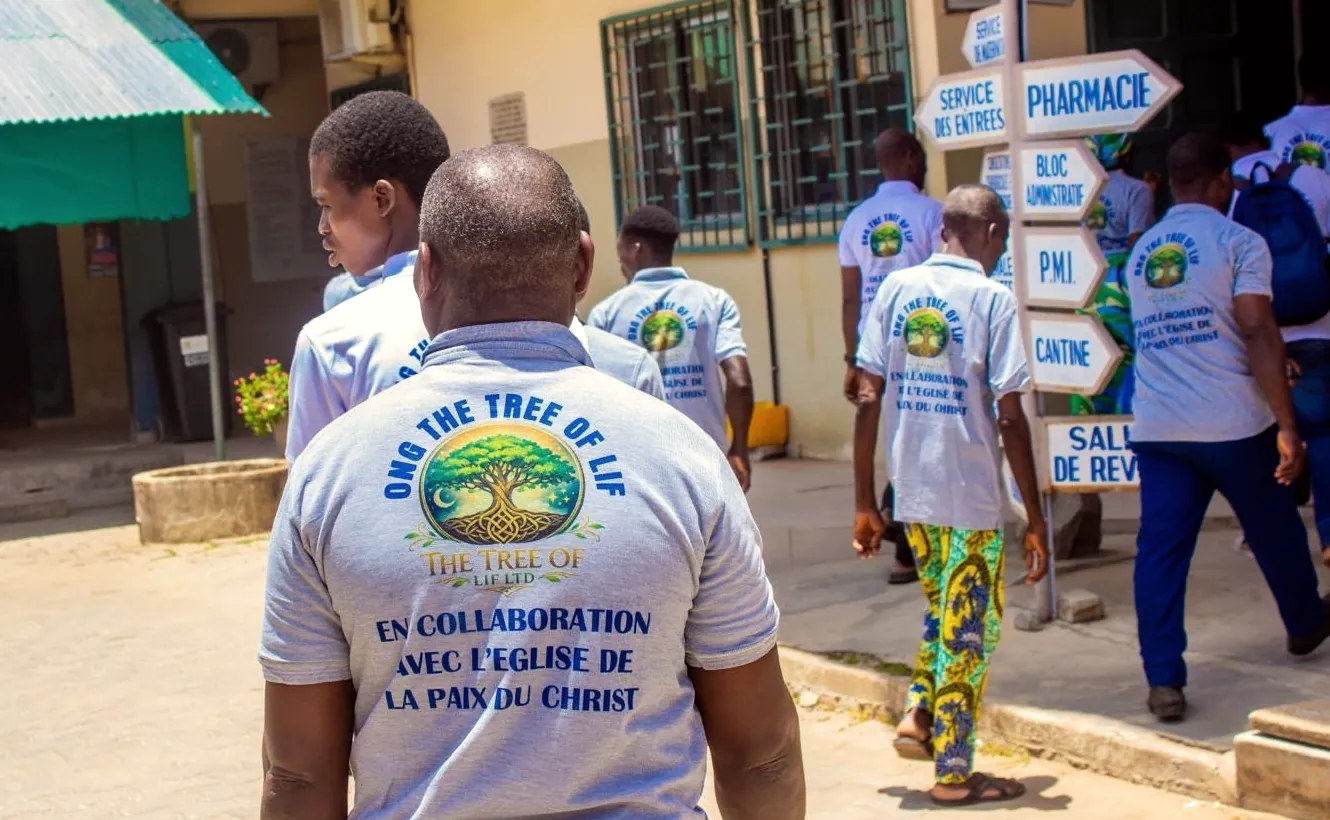 Volunteers walk into CNHU-HKM hospital; the shirt in front reads ONG The Tree of LIF, en collaboration avec l’Église de la Paix du Christ